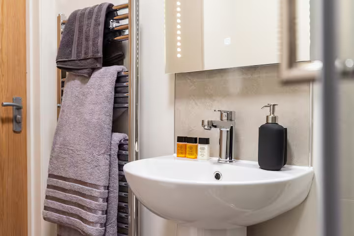 Semicircular sink and multi-rail towel rack in a bright, modern bathroom